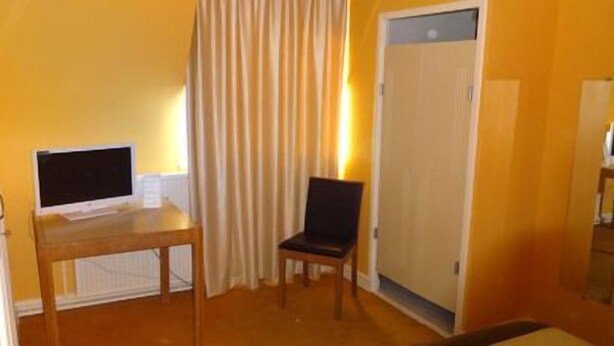 A room with a wooden table, a chair, a closed door, and a window with curtains.