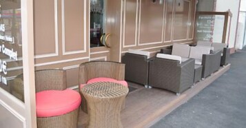 Una sección de un hotel con muebles de mimbre y un panel de vidrio.