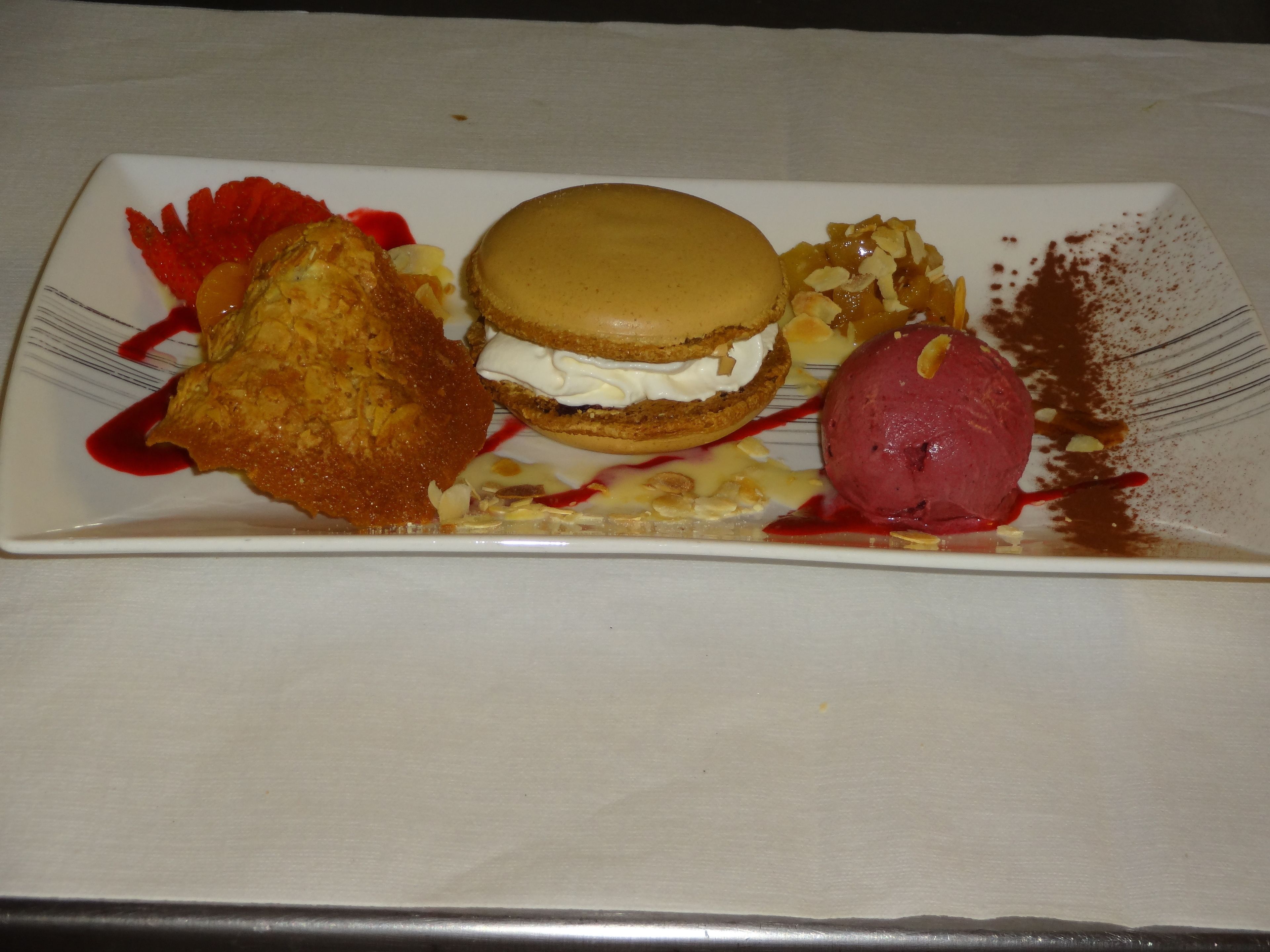 A dessert plate with a layered cake, a scoop of ice cream, and a fruit garnish.