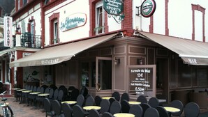 Un espace extérieur aménagé avec des tables et des chaises, une enseigne indiquant un restaurant et une enseigne de bar.