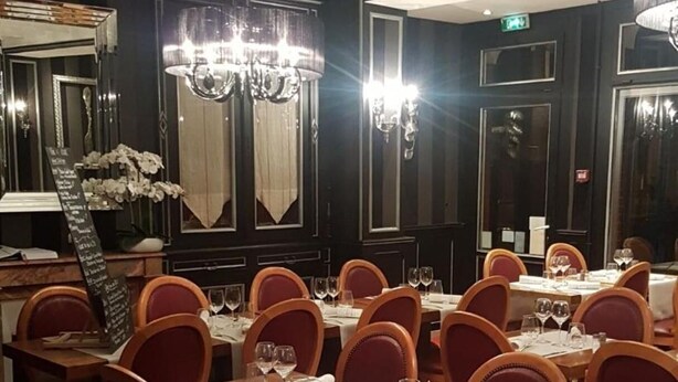 Un espace repas avec plusieurs tables dressées pour les convives, chacune étant agrémentée de chaises et de couverts.
