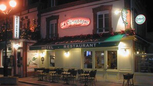 Un hôtel doté d'une terrasse et d'une enseigne lumineuse au néon.