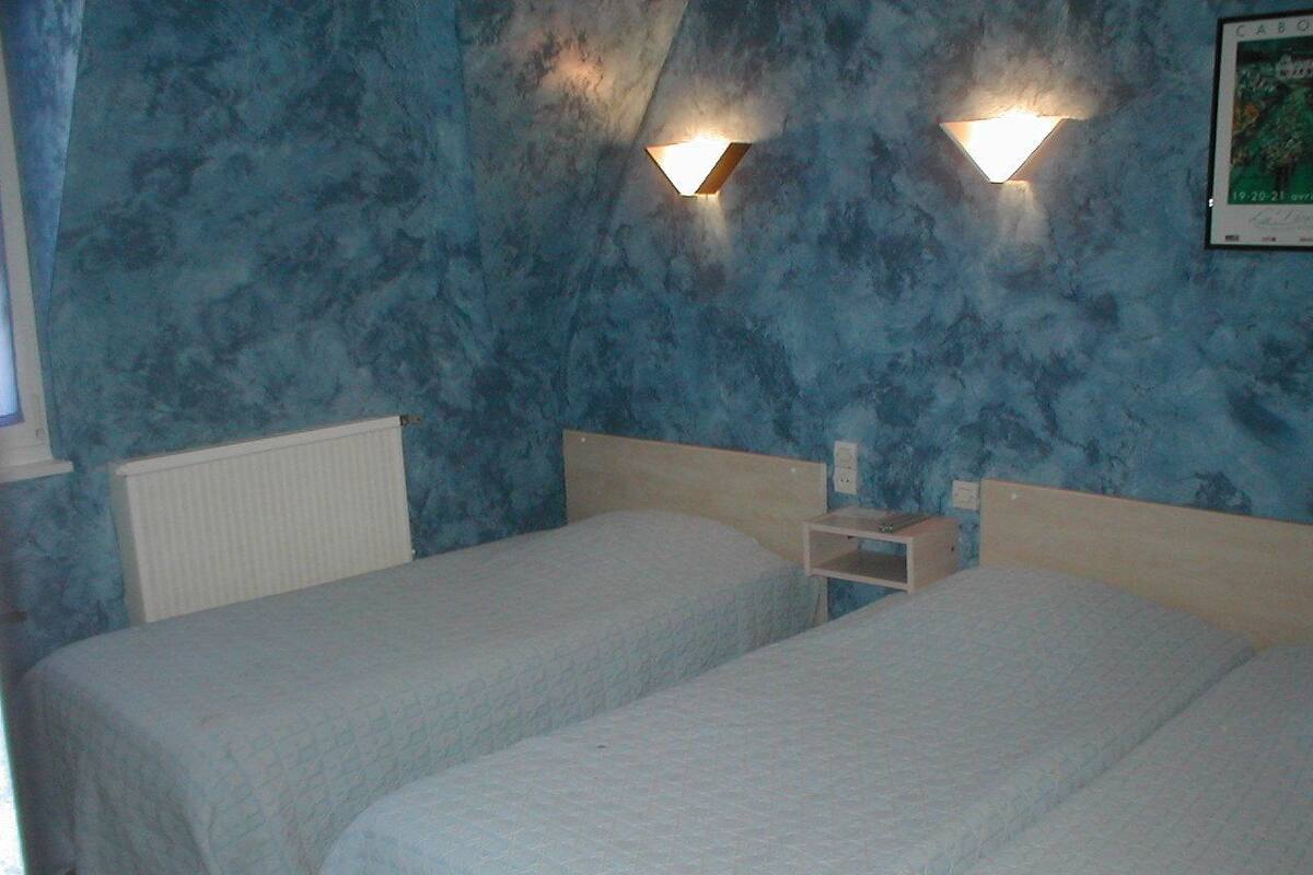 Een kamer met twee eenpersoonsbedden, een nachtkastje en een wandlamp.