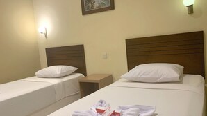 Two single beds with wooden headboards, white linens, and a pair of white towels on the bed.