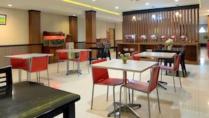 A restaurant with multiple tables and chairs, a fish tank, and a decorative wall with vertical panels.