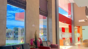 A spacious lobby with a red and black sofa, large windows, and a modern interior design.