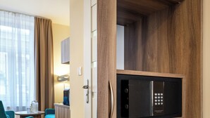 A modern hotel room with a built-in microwave, wooden flooring, a seating area with a table and chairs, and a kitchenette. - Kosmopolita Apartments (Kraków)