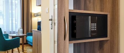 A modern hotel room with a built-in microwave, wooden flooring, a seating area with a table and chairs, and a kitchenette.