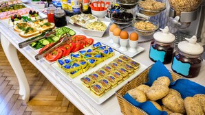 A buffet with various food items including sandwiches, fruits, cheeses, and condiments. - Kosmopolita Apartments (Kraków)