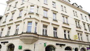 A multi-story building with a classic architectural style, featuring a corner entrance, multiple windows, and a chain-locked gate at the front. - Kosmopolita Apartments (Kraków)
