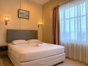 A neatly made bed with white linens, a headboard, and two wall-mounted lamps.
