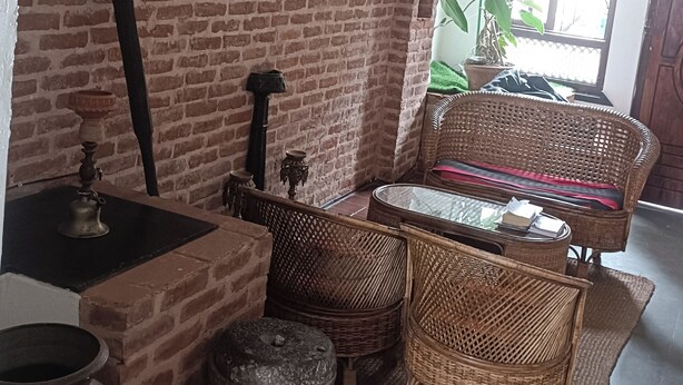 A room with a brick wall, wicker furniture, and a large window. - Easy Homes (Lalitpur)