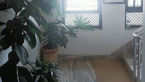 A room with a large window, a potted plant, a framed picture of a building, and a marble floor. - Easy Homes (Lalitpur)