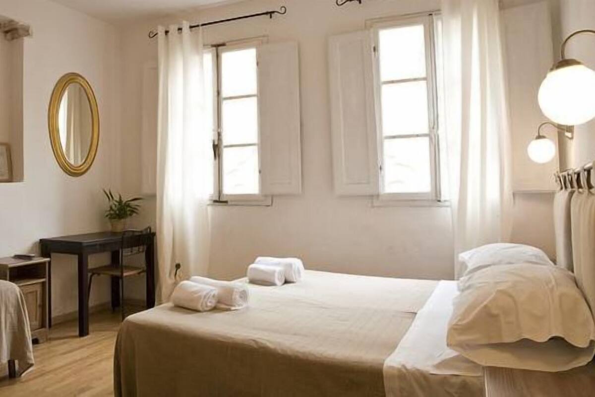A hotel room with a bed, a desk, a chair, a TV, and a mirror.