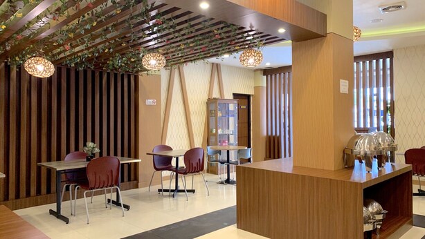 Un intérieur moderne avec des lambris en bois, un comptoir d’accueil et un espace détente comprenant des tables et des chaises.