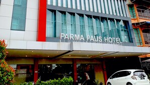 Un bâtiment moderne à la façade rouge et blanche très visible, sur laquelle on peut lire l’inscription « PARMA PAUS HOTEL ».