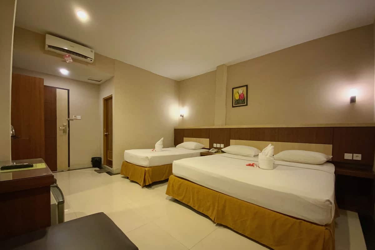 A hotel room with two beds, a desk, a chair, an air conditioning unit, and a door.