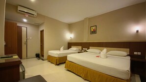 Une chambre d’hôtel avec deux lits, un bureau, une chaise, un appareil de climatisation et une porte.
