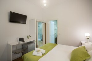 A hotel room with a bed, a desk with a laptop, a TV, and a mirror. - HA San Mateo Suites (Madrid)
