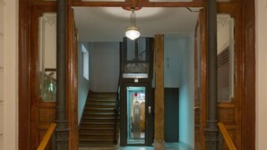 Una gran escalera con barandales de madera y un candelabro, que conduce a un rellano del segundo piso.