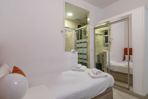 A hotel room with a bed, a bathroom with a shower, and a mirror reflecting the room. - HA San Mateo Suites (Madrid)