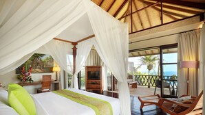 A bedroom with a canopy bed, a TV, a wooden chair, and a balcony with a view of the ocean. - The Cliff Hotman Paris VI Pandawa (Kutuh)