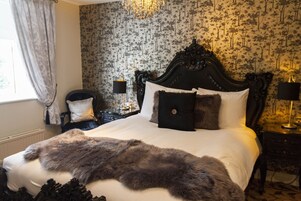 Un dormitorio con una cama grande, un cabecero decorado y papel tapiz con motivos florales.