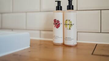 Two bottles of Brambley hand wash on a wooden surface with a white tiled wall in the background.