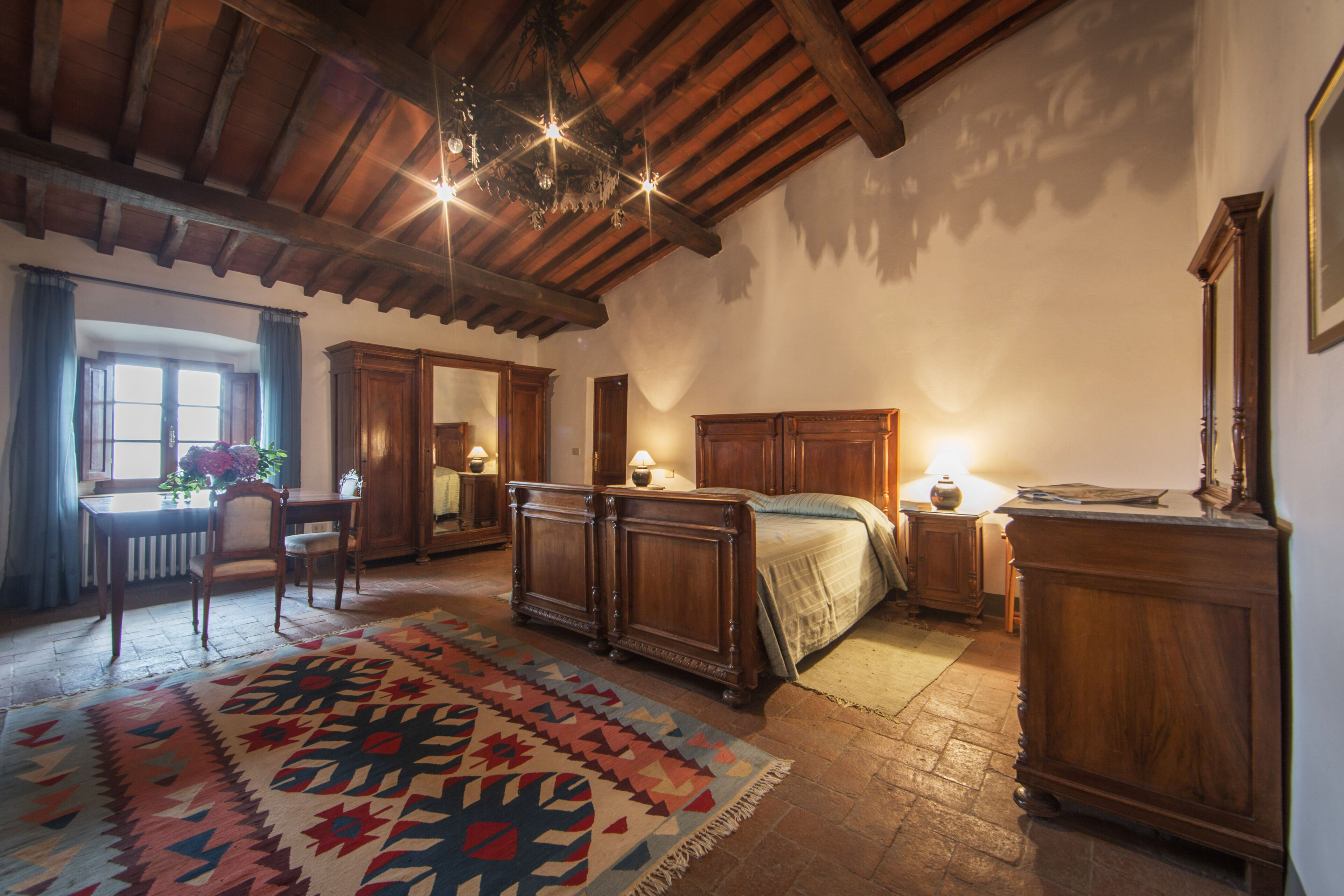 A traditional room with a wooden ceiling, a bed, a desk, and a chair.