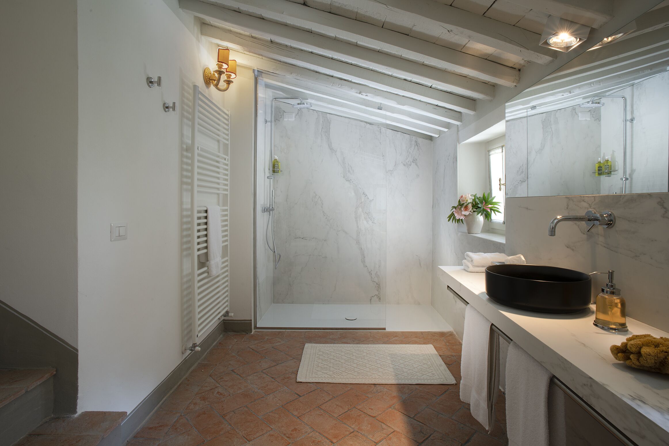 Une salle de bain moderne avec une douche, un lavabo doté d’un receveur rond et un grand miroir.