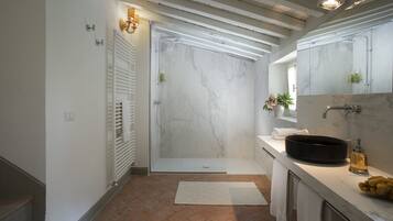 Une salle de bain moderne avec une douche, un lavabo doté d’un receveur rond et un grand miroir.