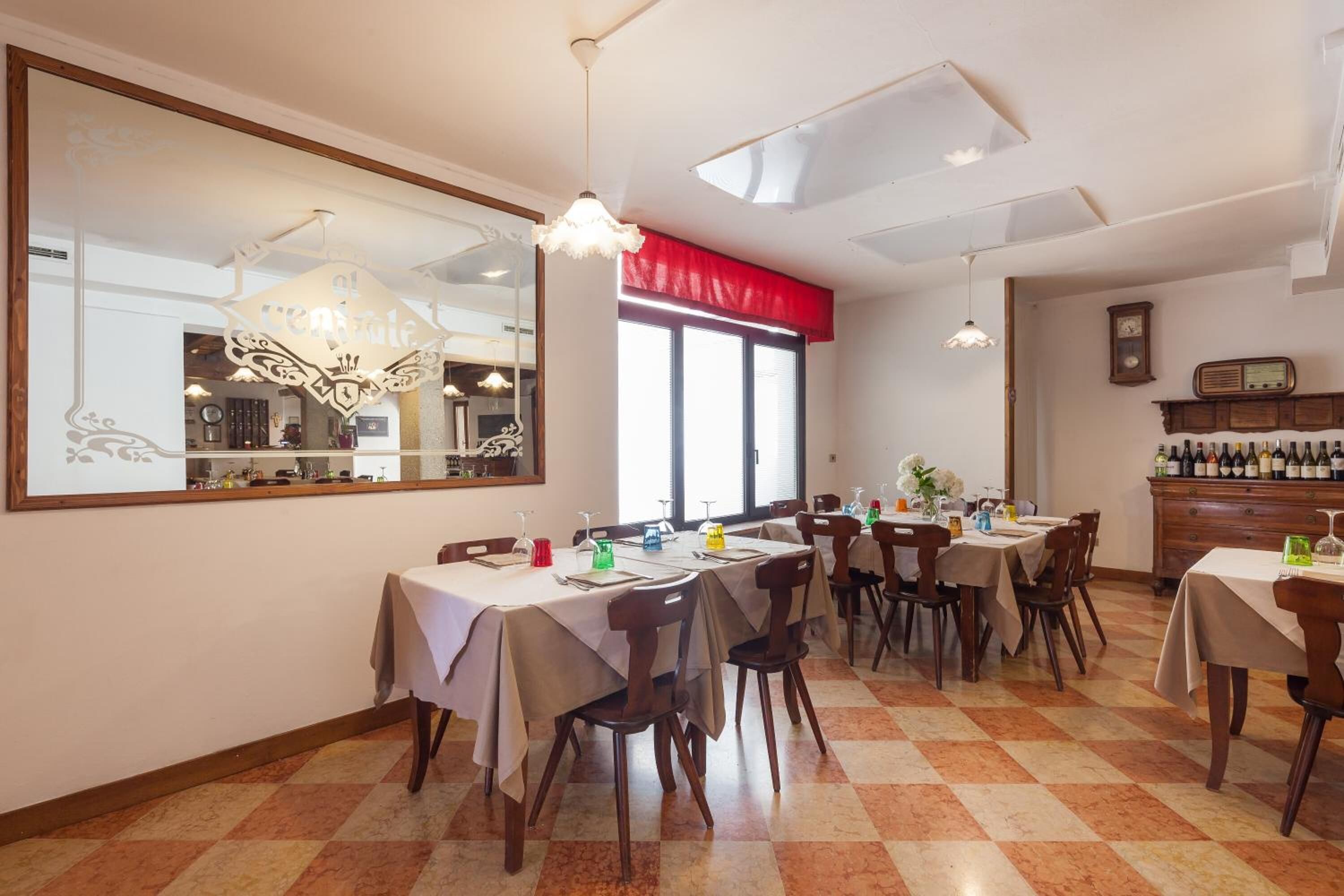A dining area with tables set for service, a large mirror, and a wine rack.