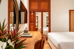 Ein Hotelzimmer mit einem Holztisch, einem Bett, einem Spiegel und einer Tür zu einem weiteren Raum.
