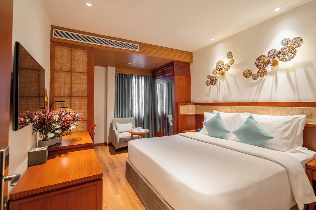 Une chambre d’hôtel avec un grand lit, un bureau avec une chaise, une petite table et un téléviseur.