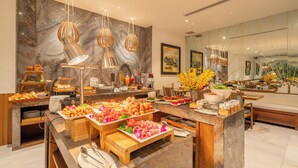A buffet setup with various food items and a marble wall. - A&EM Art Hotel (Ho Chi Minh City)