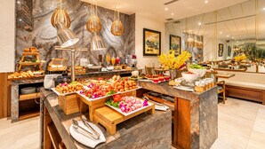 Un buffet proposant une variété de plats, un mur en marbre et des luminaires modernes.