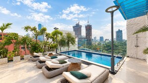 Área de piscina no terraço com espreguiçadeiras e plantas em vasos.