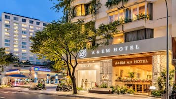 Hotel com fachada moderna, entrada imponente e área de estacionamento visível.