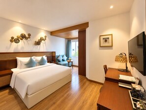 Ein Hotelzimmer mit einem großen Bett, einem Schreibtisch mit Lampe und einem Fernseher.
