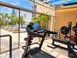 Une salle de sport équipée d'un tapis de course, d'un banc de musculation et de poids libres.