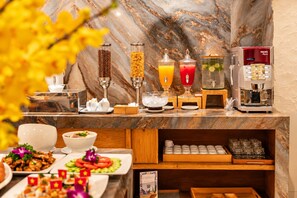 Un buffet de petit-déjeuner proposant un choix varié d’aliments, une machine à café et un distributeur de jus.