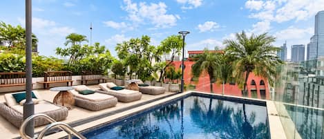 A rooftop pool area with lounge seating and a view of the city skyline.