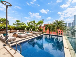Zona de piscina en la azotea con asientos de descanso y vistas al horizonte de la ciudad.