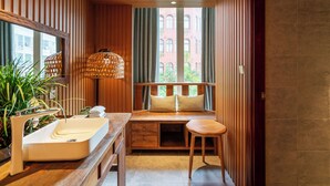 Een moderne badkamer met een houten wastafelmeubel, een wastafel en een zitbankje met kussens.