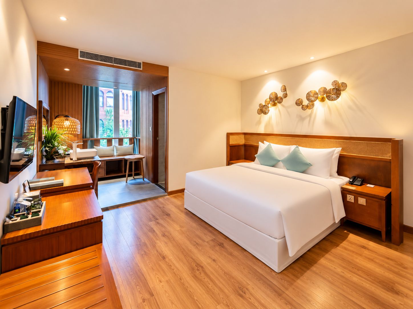 Quarto de hotel com cama, mesa de cabeceira e escrivaninha com cadeira.