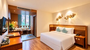 Quarto de hotel com cama, mesa de cabeceira e escrivaninha com cadeira.
