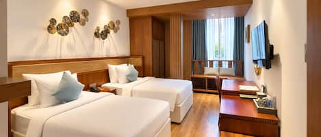 Habitación de hotel con dos camas, un escritorio, un televisor y una ventana con cortinas.