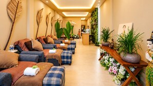 Un espace spa doté de plusieurs coins salon, d’un comptoir d’accueil et de plantes décoratives.