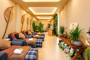 Un espace spa doté de plusieurs coins salon, d’un comptoir d’accueil et de plantes décoratives.
