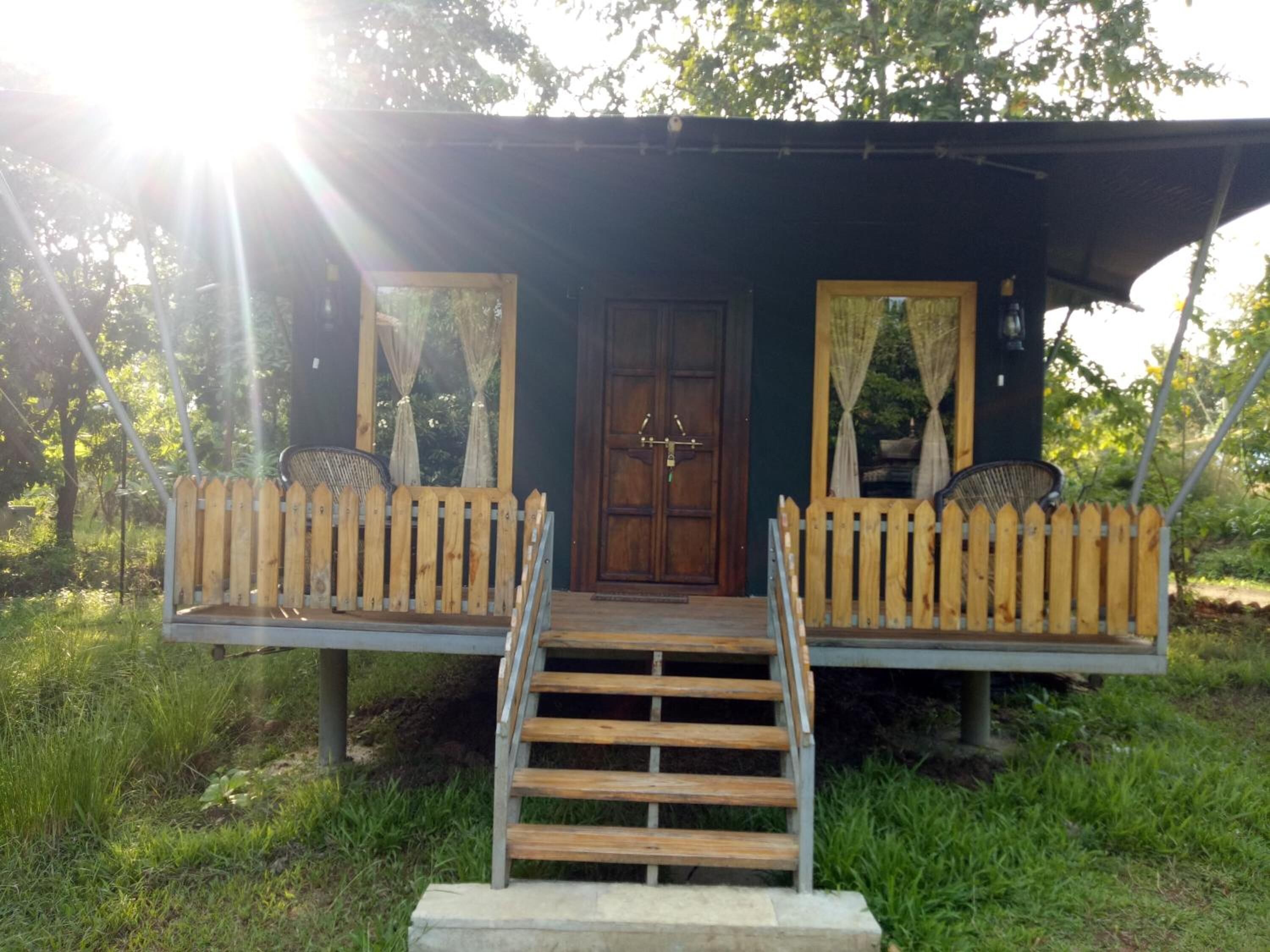 A wooden cabin with a porch, a wooden staircase, and a door with a lock.